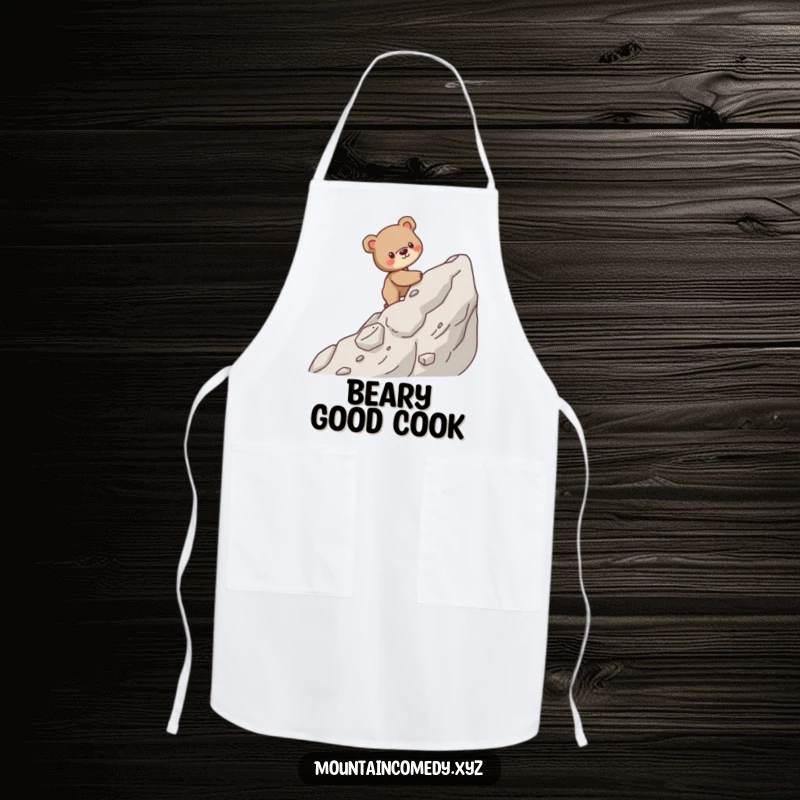 Funny apron featuring a sturdy bear cub character carefully climbing a steep, rocky mountain, ideal for kitchen determination.