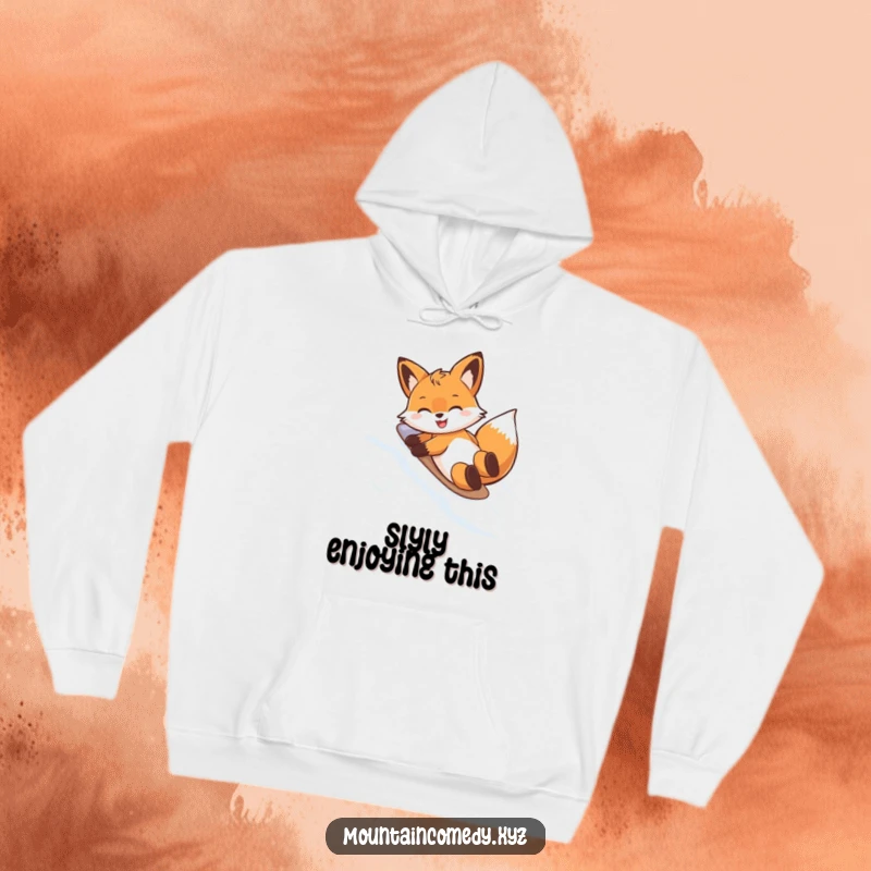 Funny hoodie depicting a happy fox character doing a belly slide on a snowy mountain, perfect for cozy, humorous winter vibes.